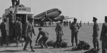 Indian Army soldiers during the 1947 Kashmir operation unloading equipment from a military truck beside a Douglas C-47 transport aircraft on an airfield, preparing to defend Srinagar during the first Indo-Pak war.