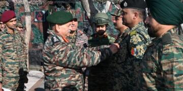Army Chief pins a decoration on a soldier while interacting with troops at a forward post in a border area.